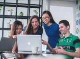 Team of four people working behind a laptop.
