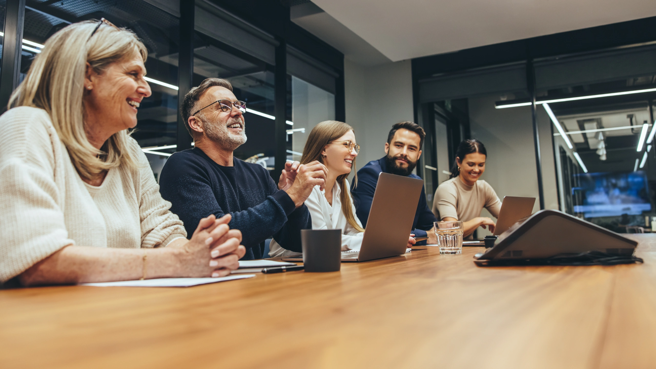 Five people looking and listening to a presentation in a meeting room.
